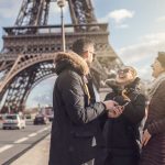 Grupo de amigos conversando y riendo en francés junto a la torre Eiffel